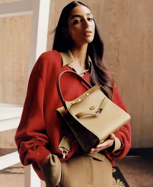 A woman wearing a Tony Burch red sweater with a brown purse