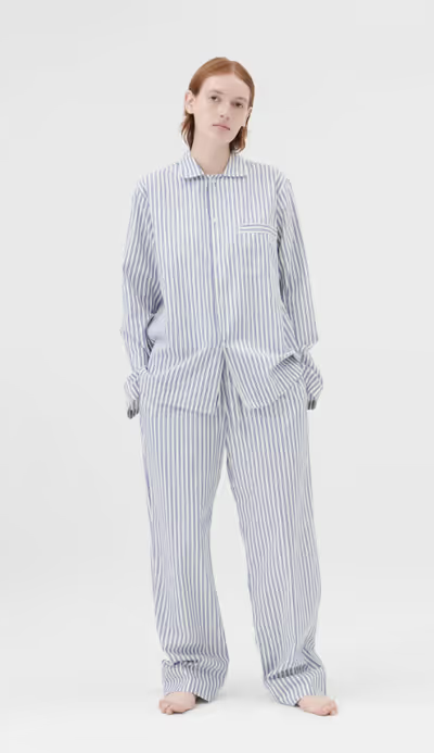 A woman wearing a Tekla pajama outfit in blue and white stripes
