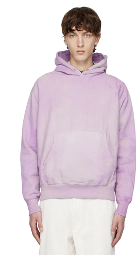 A man wearing a lavender Whim Golf hoodie with white pants