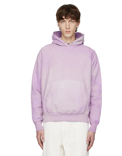 A man wearing a lavender Whim Golf hoodie with white pants