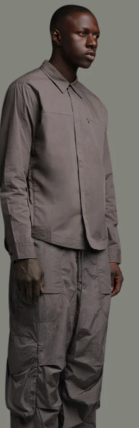 A man wearing a dark grey Entire Studios outfit with matching shirt and pants