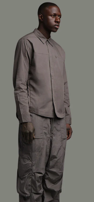 A man wearing a dark grey Entire Studios outfit with matching shirt and pants