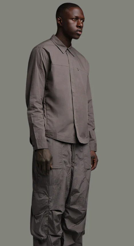 A man wearing a dark grey Entire Studios outfit with matching shirt and pants