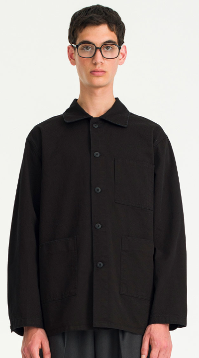 A man wearing a black button up Olive Shirt with glasses