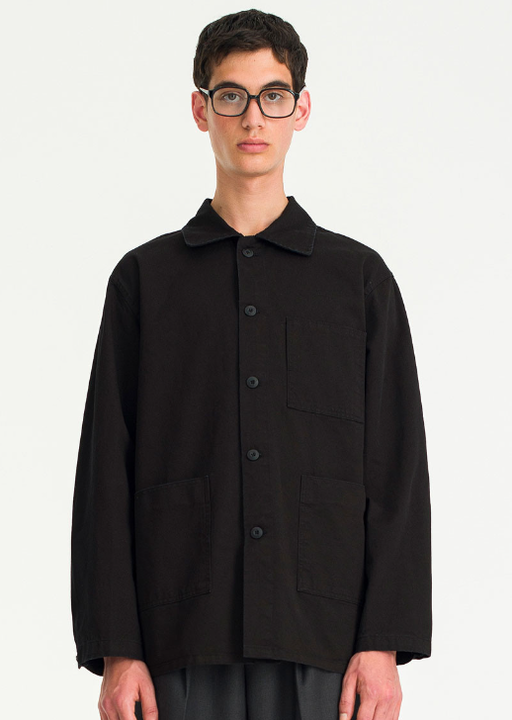 A man wearing a black button up Olive Shirt with glasses