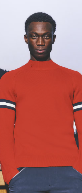 A man wearing a red Perfect Moment sweater and navy blue pants