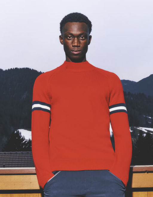 A man wearing a red Perfect Moment sweater and navy blue pants