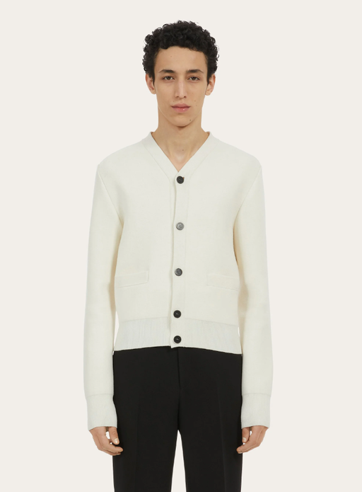 A man wearing a white Ferragamo cardigan and black pants