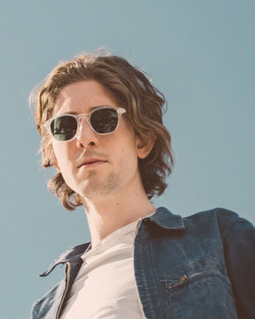 A man wearing a pair of light grey Sunski sunglasses