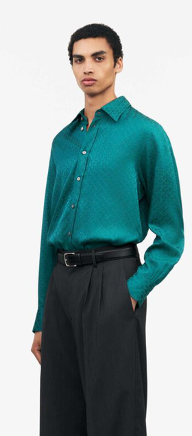 A man wearing a Tiger of Sweden green button up with black pants