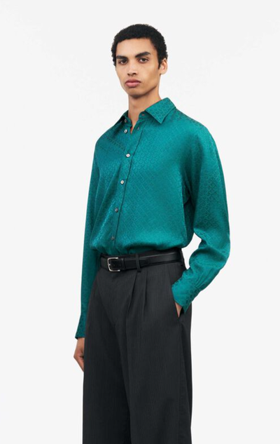 A man wearing a Tiger of Sweden green button up with black pants