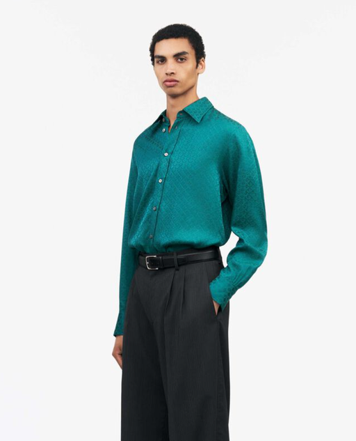 A man wearing a Tiger of Sweden green button up with black pants