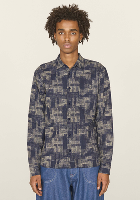 A man wearing a YMC all over print button up and blue jeans