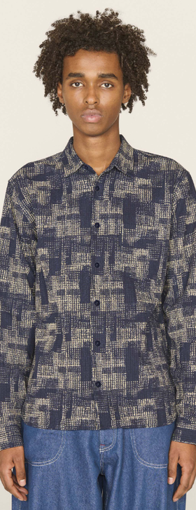 A man wearing a YMC all over print button up and blue jeans