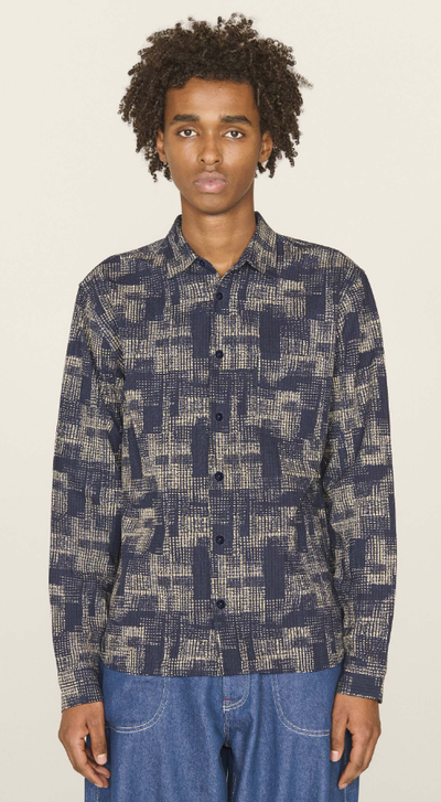 A man wearing a YMC all over print button up and blue jeans