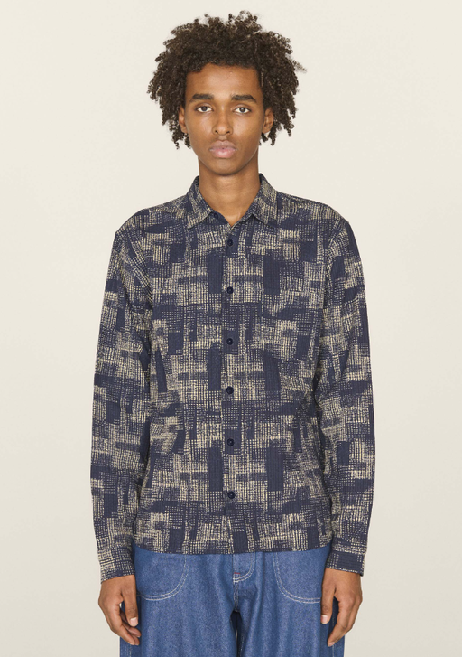 A man wearing a YMC all over print button up and blue jeans