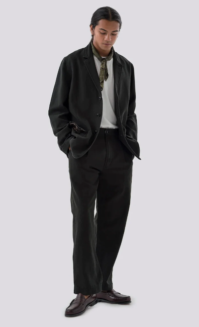 A man wearing a black Maharishi suit with a hankerchief