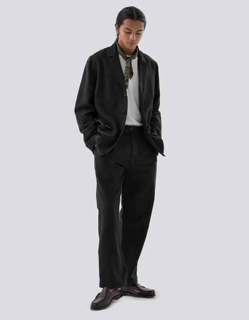 A man wearing a black Maharishi suit with a hankerchief