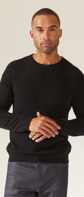 A man wearing a tight-fitting black Italic sweater and grey jeans