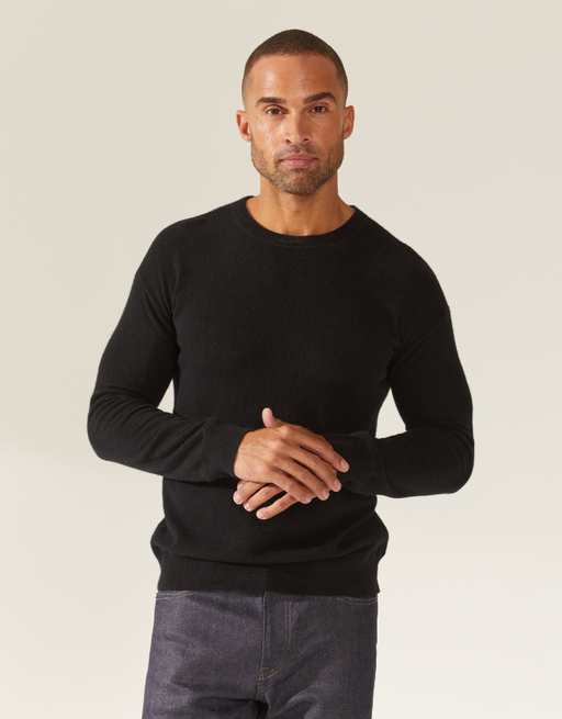 A man wearing a tight-fitting black Italic sweater and grey jeans