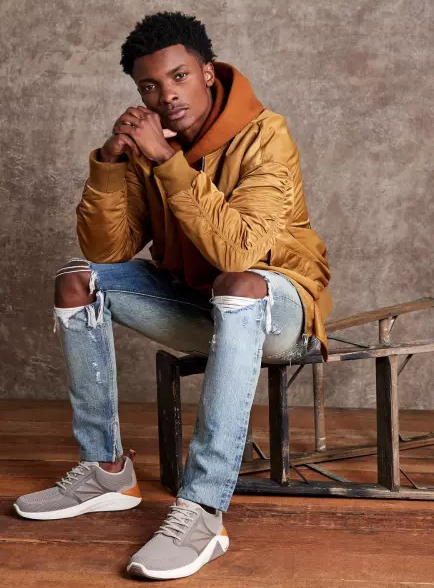 A man wearing a grey Skechers with white soles