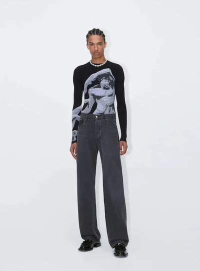 A man wearing a tight-fitting black EYTYS shirt with Michaelangelo on it