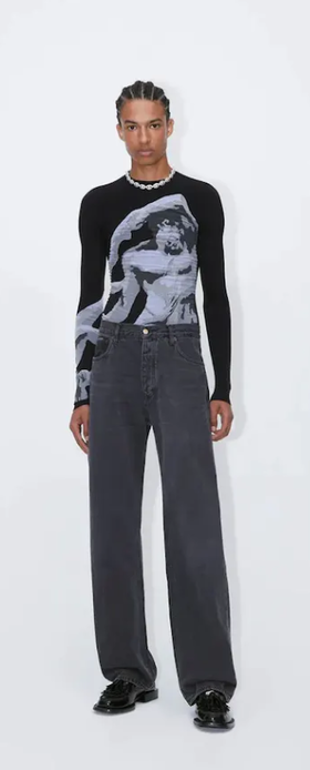 A man wearing a tight-fitting black EYTYS shirt with Michaelangelo on it