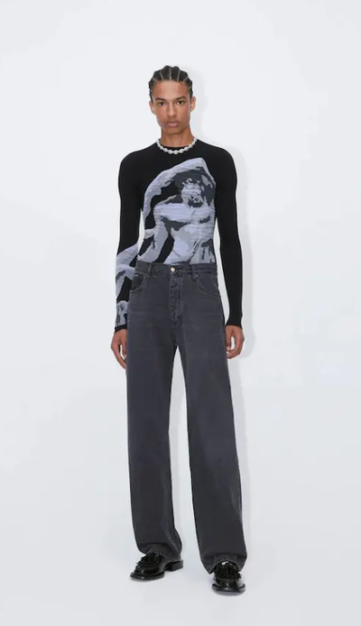 A man wearing a tight-fitting black EYTYS shirt with Michaelangelo on it