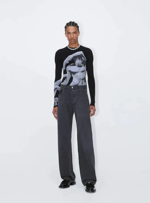 A man wearing a tight-fitting black EYTYS shirt with Michaelangelo on it
