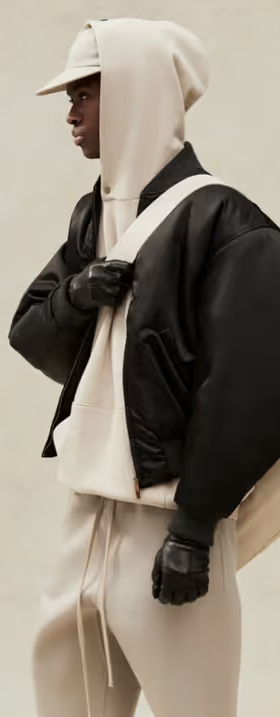 A man wearing a cream Fear of God Essentials hoodie, jacket and matching sweatpants