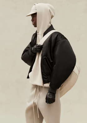 A man wearing a cream Fear of God Essentials hoodie, jacket and matching sweatpants