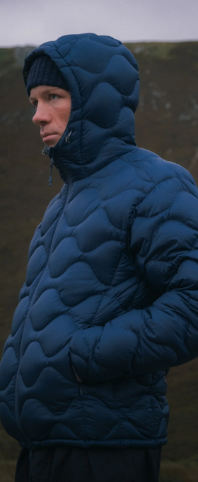A man wearing a puffy blue Kestin jacket with a black beanie