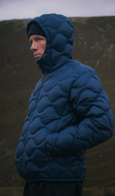 A man wearing a puffy blue Kestin jacket with a black beanie