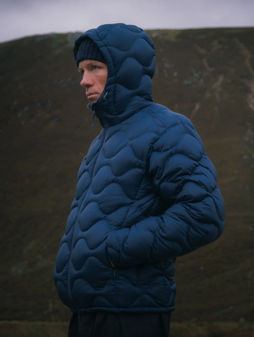 A man wearing a puffy blue Kestin jacket with a black beanie