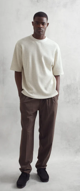 A man wearing a loose-fitting white Wax London t-shirt and dark pants