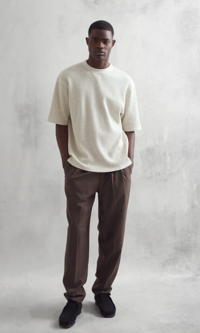 A man wearing a loose-fitting white Wax London t-shirt and dark pants