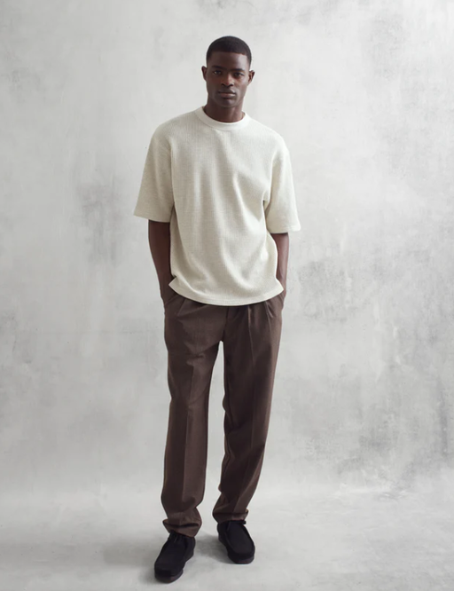 A man wearing a loose-fitting white Wax London t-shirt and dark pants