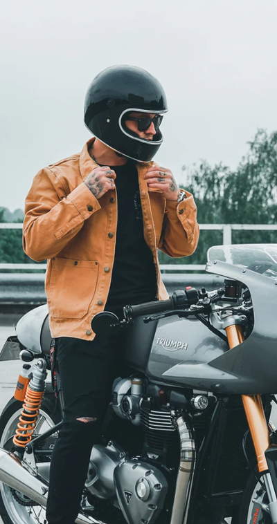 A man wearing a brown Floyd leather jacket while riding a motorcycle