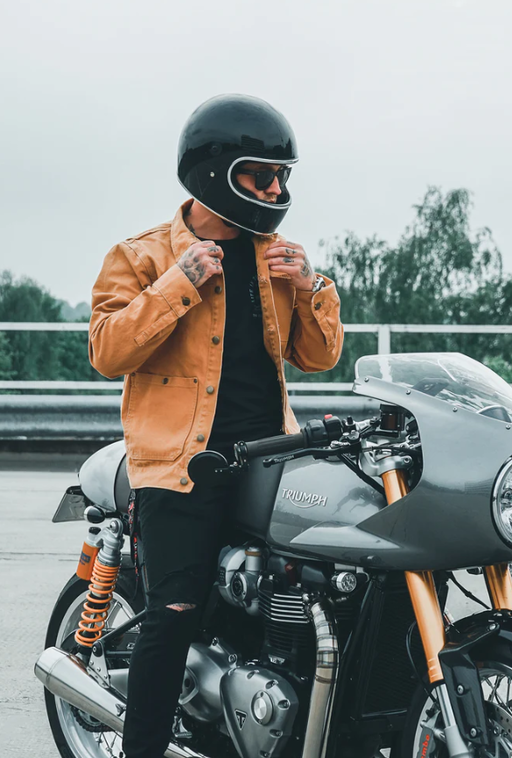 A man wearing a brown Floyd leather jacket while riding a motorcycle