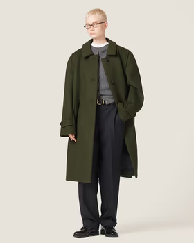 A woman wearing an oversize green trench coat by Miu Miu