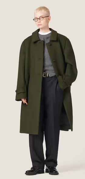 A woman wearing an oversize green trench coat by Miu Miu