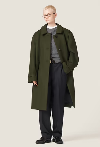 A woman wearing an oversize green trench coat by Miu Miu