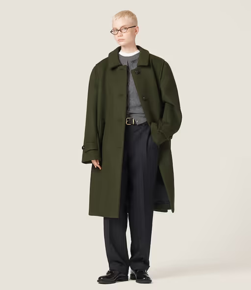 A woman wearing an oversize green trench coat by Miu Miu