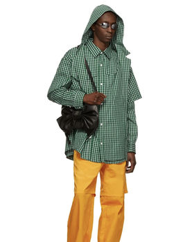 A man wearing a green checkered Hood By Air jacket and yellow pants