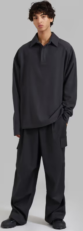 A man wearing a black 'The Frankie Shop' button-up and black pants