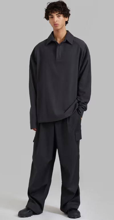 A man wearing a black 'The Frankie Shop' button-up and black pants