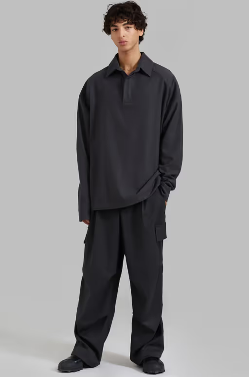 A man wearing a black 'The Frankie Shop' button-up and black pants