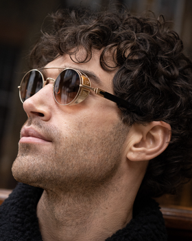 A man wearing a pair of Matsuda gold-rimmed circular sunglasses