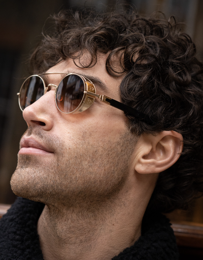 A man wearing a pair of Matsuda gold-rimmed circular sunglasses