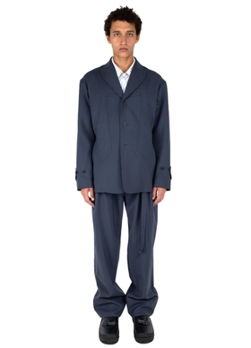 A man wearing a dark navy Kiko Kostadinov suit